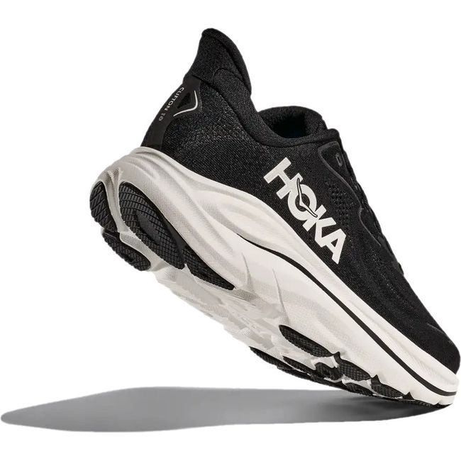 Heel angled up showing tread of Women's Hoka Clifton 10 Running Shoe in black and white