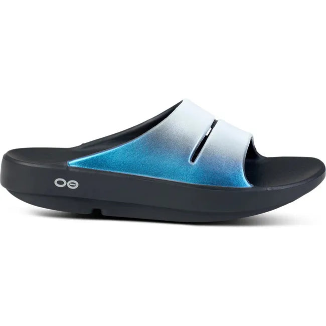 Lateral side of Women's OOfos OOahh Luxe Slide Sandal in Frost silver and blue