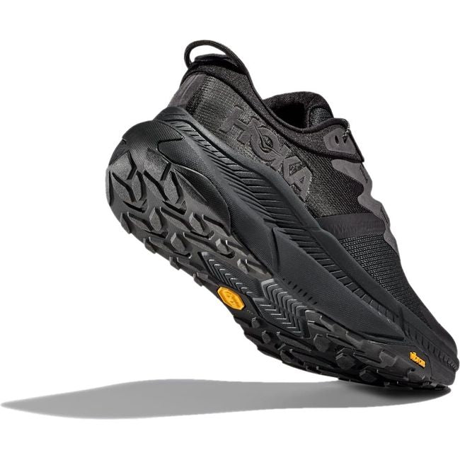 Heel angled up showing Vibram sole of Men's Hoka Transport Lifestyle Shoe in all black