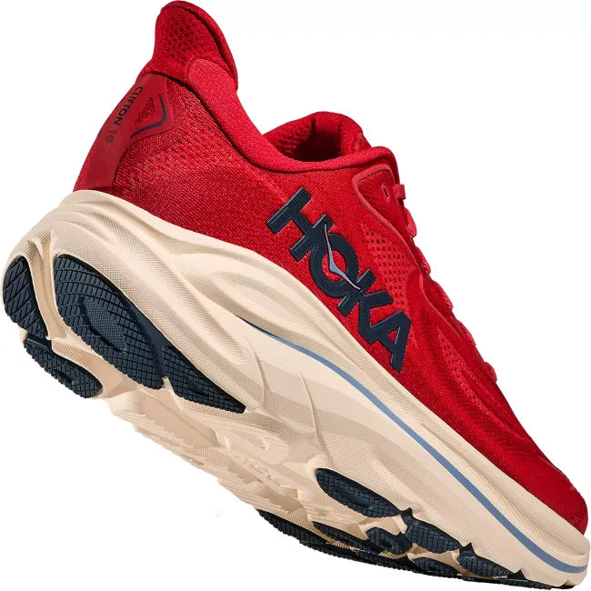 Close-up rear lateral view of Hoka Clifton 10 in Vermillion showing oversized midsole stack, MetaRocker, and navy abrasion rubber outsole