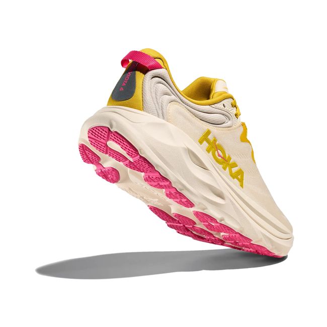 Rear lateral angle of Hoka Gaviota 6 in birch and yellow gold showing comfort collar, heel pull webbing, and pink outsole