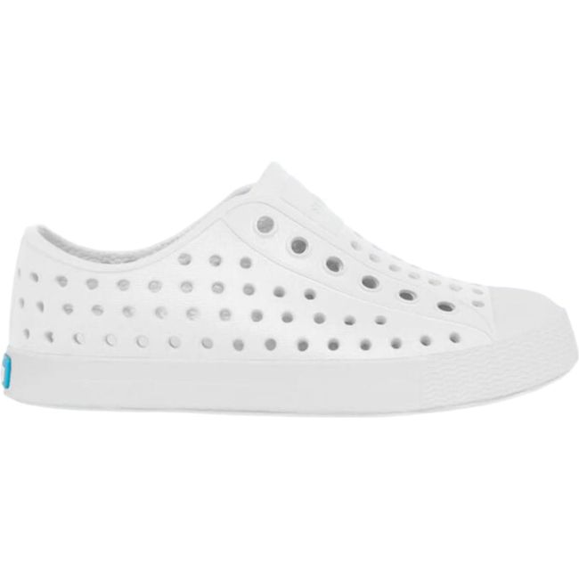 Lateral side view of the Native Kids' Jefferson Shoe in shell white, featuring a slip-on design, lightweight and hand-washable Sugarlite™ material, a perforated upper similar to Crocs, a white toe cap, and a white sole.