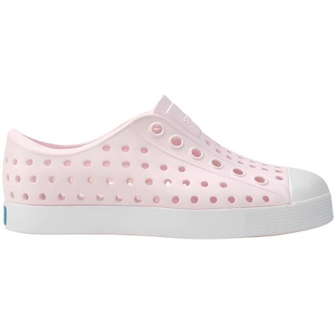 Lateral side view of the Native Kids' Jefferson Shoe in pink, featuring a slip-on design, lightweight and hand-washable Sugarlite™ material, a perforated upper similar to Crocs, and a white toe cap for added design.