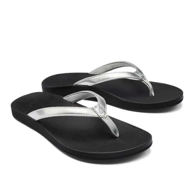Pair of Women's Olukai Puawe Flip Flop with a silver upper and black sole.