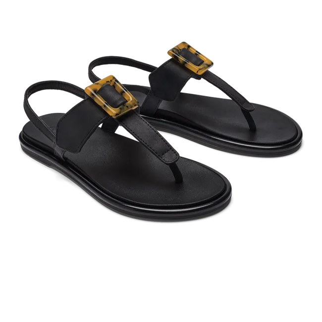 Pair of womens Olukai Lai T Bar sandal in black leather with a backstrap. Brown buckle on instep