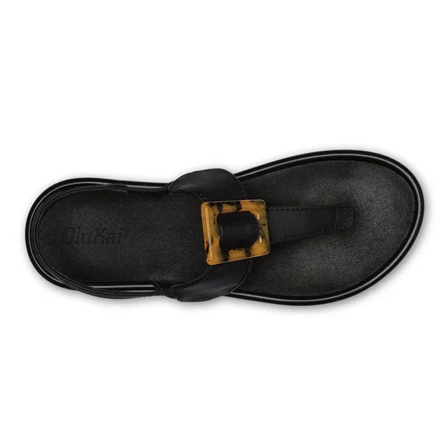 Top down view of women's Olukai Lai T Bar sandal in black leather with brown buckle on instep