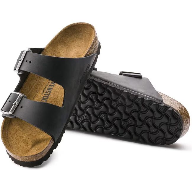 A pair of black Birkenstock Arizona. One showing the sole and the other showing the leather upper.