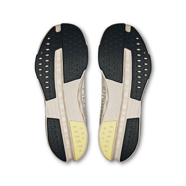 Soles of On Running Women's Cloudsurfer Next Running Shoes in ivory and silver with black tread