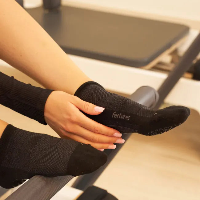 Women's Feetures Elite Grip Sock in Balance Black, shown on foot during Pilates stretch with grips