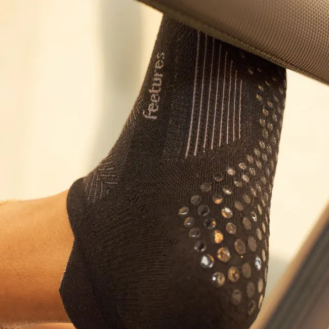 Close up of grips on the sole of Women's Feetures Elite Grip Max Cushion Tab Sock in Balance Black