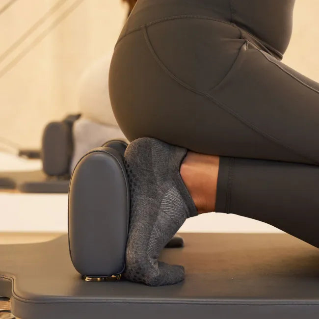 Women's Feetures Elite Grip Sock in Flow Gray, worn during kneeling stretch with grip soles