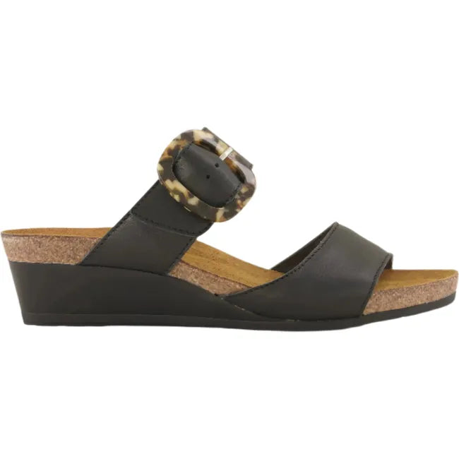 Lateral side view of Naot Women's Kingdom Wedge Sandal in black, featuring an oversized buckle, a 1.75-inch polyurethane wedge heel, and a suede-wrapped anatomic cork and latex footbed.