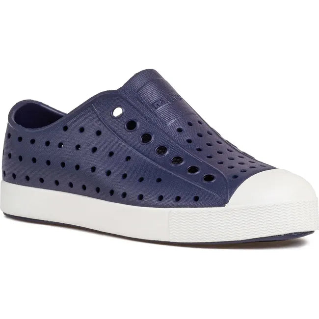 Lateral side angled view of the Native Kids' Jefferson Shoe in navy blue, featuring a slip-on design, lightweight and hand-washable Sugarlite™ material, a perforated upper similar to Crocs, and a white toe cap for added design.