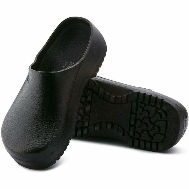 View of a pair of black Birkenstock Professional Super Birki clogs for healthcare and utility, with one shoe displaying the nonslip oil- and grease-resistant sole, while the other shoe leans against it, showing the top view, including the water-resistant polyurethane exterior.