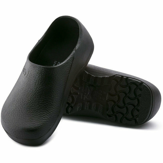 View of a pair of Black Birkenstock Professional Profi Birki healthcare and utility clogs, with one shoe displaying the nonslip, oil- and grease-resistant PU sole, and the other shoe leaning against it to show the top view, including &#39;Birki&#39;s&#39; engraving on the right side of the instep.